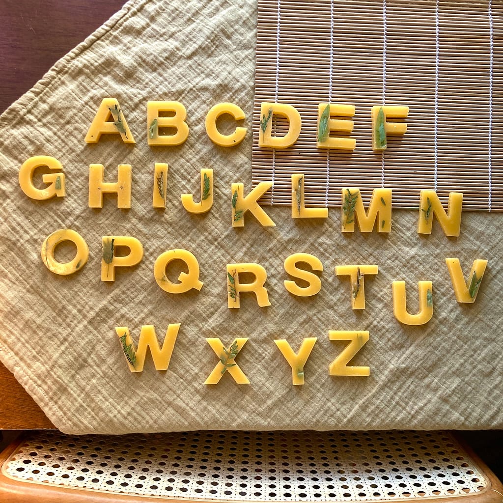 beeswax letters with pressed flowers. the alphabet is displayed in order. 